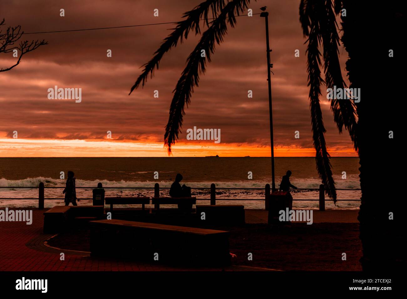 The sky lights up at sunset over the Atlantic as seen from the popular promenade off Sea Point, Cape Town, South Africa. Stock Photo