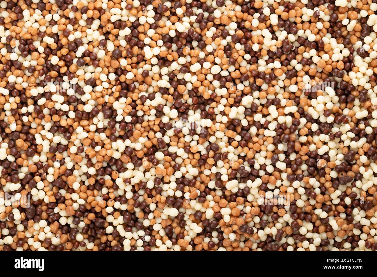 Chocolate mini pearls, background. Extra crunchy sprinkles, made of grain extrudate, covered with white, milk and dark chocolate. Used as sweet decor. Stock Photo