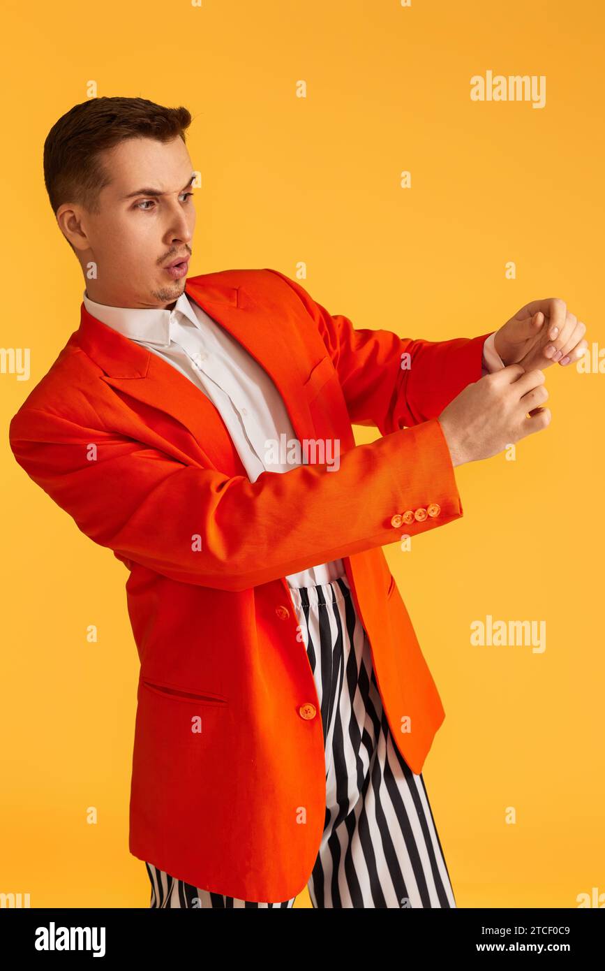 fashionable funny young man in orange jacket and striped pants on ...