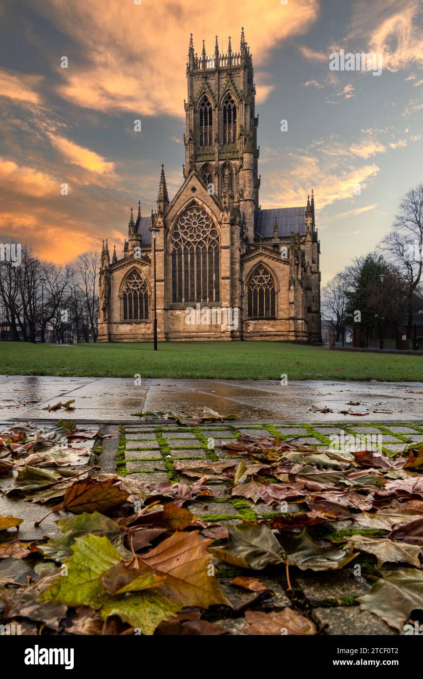 DONCASTER, UK - DECEMBER 8, 2023.  A vertorama of The Minster Church of St George in Doncaster, South Yorkshire at sunset with Autumn leaves and copy Stock Photo