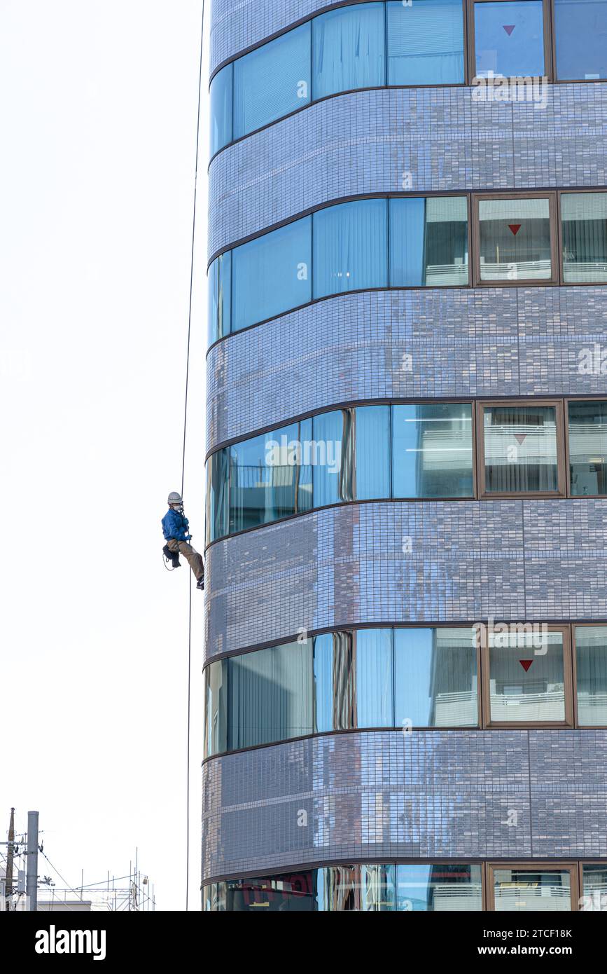 worker abseils with a rope to carry out maintenance on a building Stock Photo