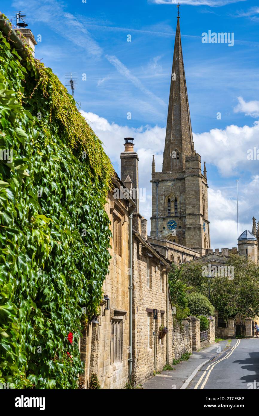 View of tower and steeple of the Church of St John the Baptist from Lawrence Lane in Burford, Oxfordshire, England, UK Stock Photo