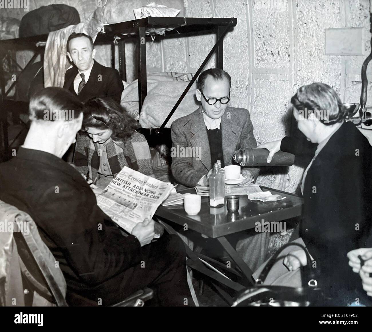 UNDERGROUND SHELTER . A husband a wife (Mr and Mrs Vangrove)  share their table  at Holborn Underground  station in July 1944  while the man at left reads about the advance on Caen. Stock Photo