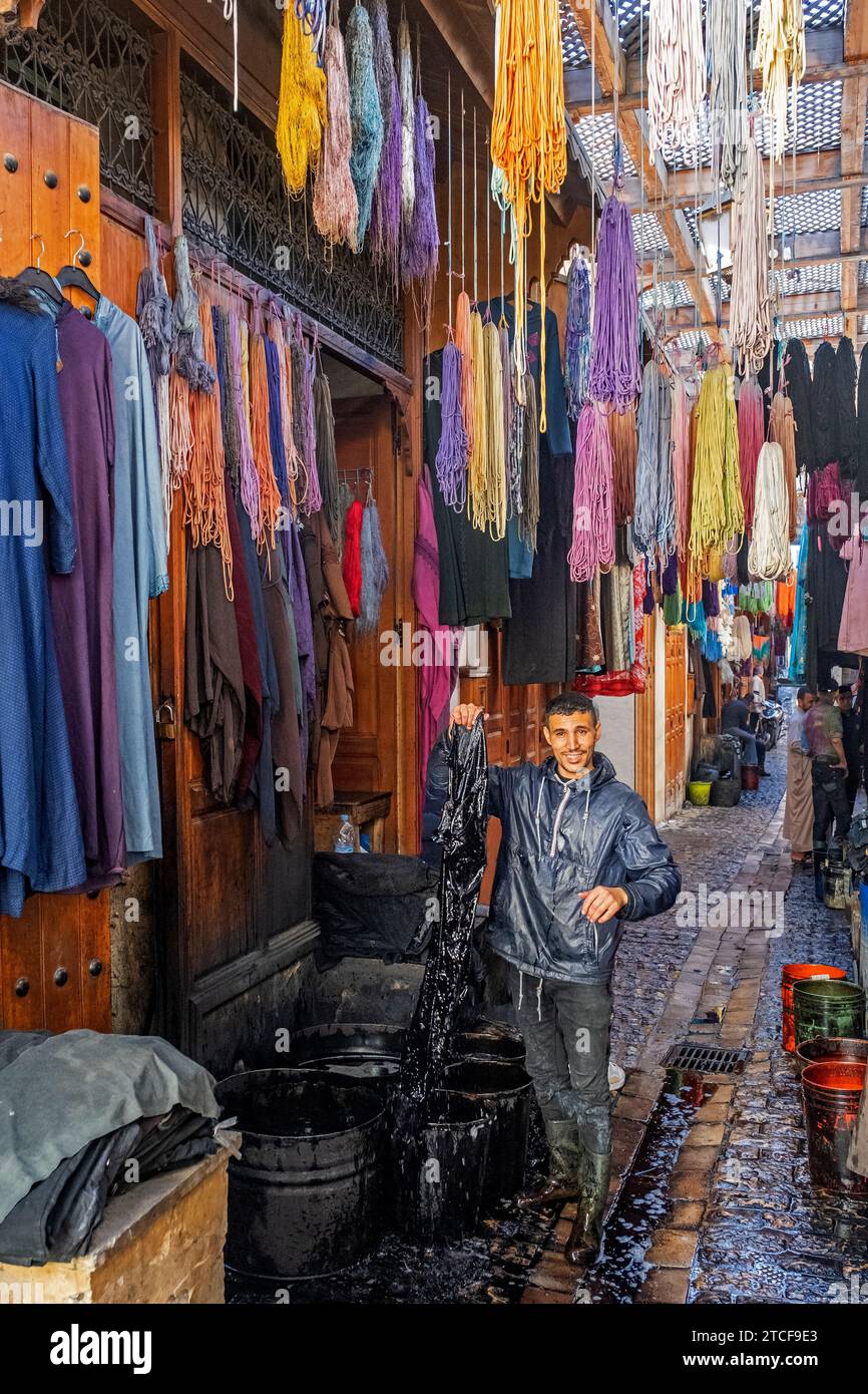 Moroccan man dyeing yarns and fabrics in alley of medina in the city Fes / Fez, Fez-Meknes, Morocco Stock Photo