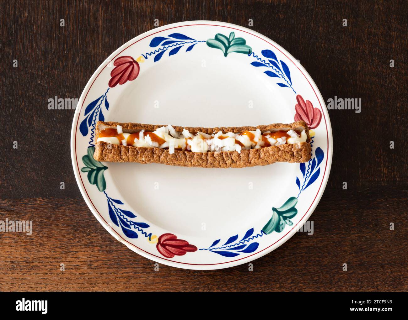 Frikandel speciaal, a popular dutch fast food snack consisting of minced meat sausage, mayonnaise, curry and chopped raw onion Stock Photo