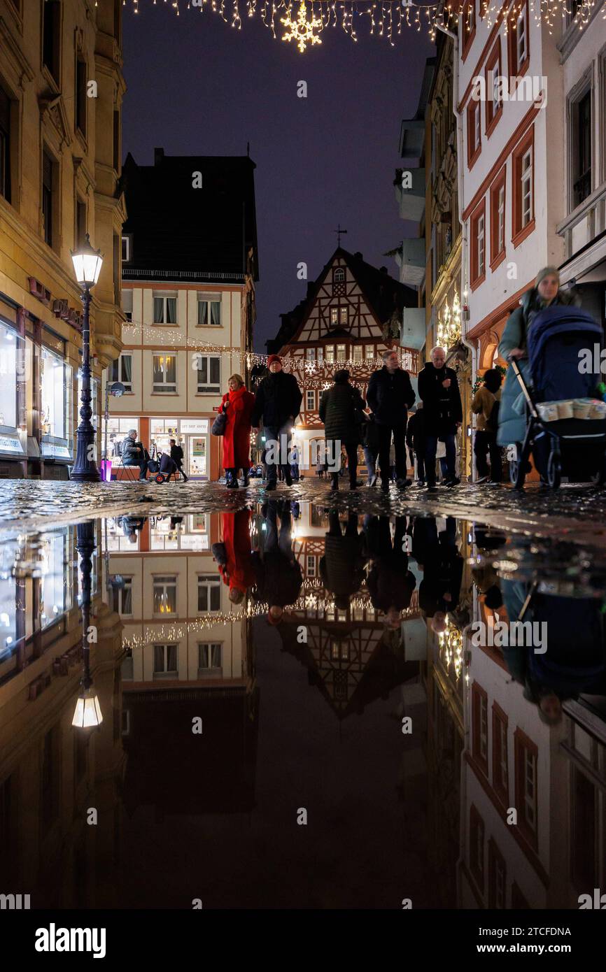 Mainzer Altstadt zum abendlichen Weihnachtsshopping Mainz, 12.12.2023 Passanten schlendern zwischen den Geschäften In einer Regenpfütze spiegelt sich die Szenerie Mainzer Altstadt zum abendlichen Weihnachtsshopping Shoppen Weihnachten, Einkaufen, Konsum, Einzelhandel Innenstadt Geschenke Präsente bunte Lichter, Reflexionen Weihnachtsstimmung Abend Mainz Innenstadt Rheinland-Pfalz Deutschland *** Mainz old town for evening Christmas shopping Mainz, 12 12 2023 Passers-by stroll between the stores The scenery is reflected in a puddle of rain Mainz old town for evening Christmas shopping Shopping Stock Photo