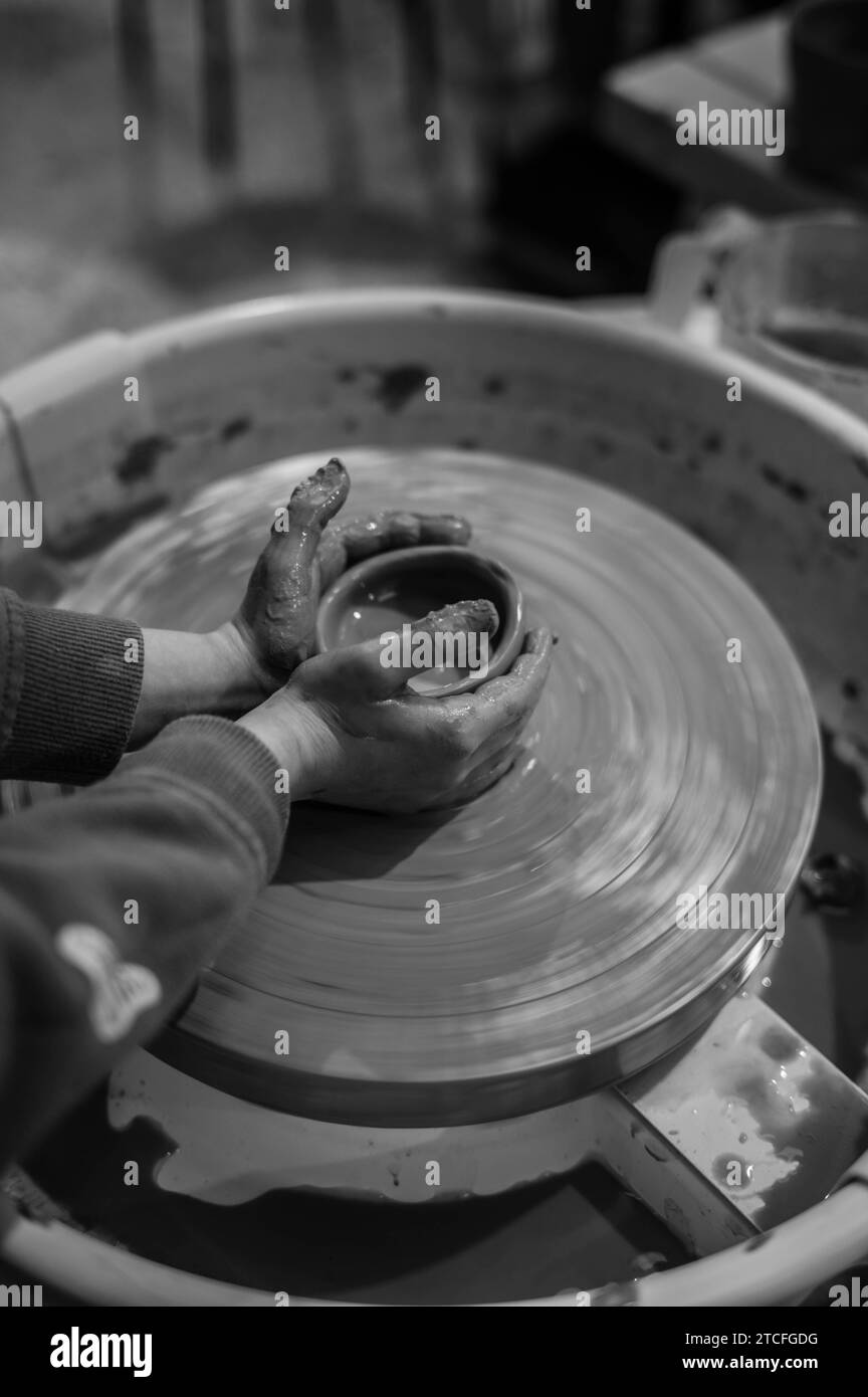 A person is crafting a pottery item on a wheel throwing device Stock Photo