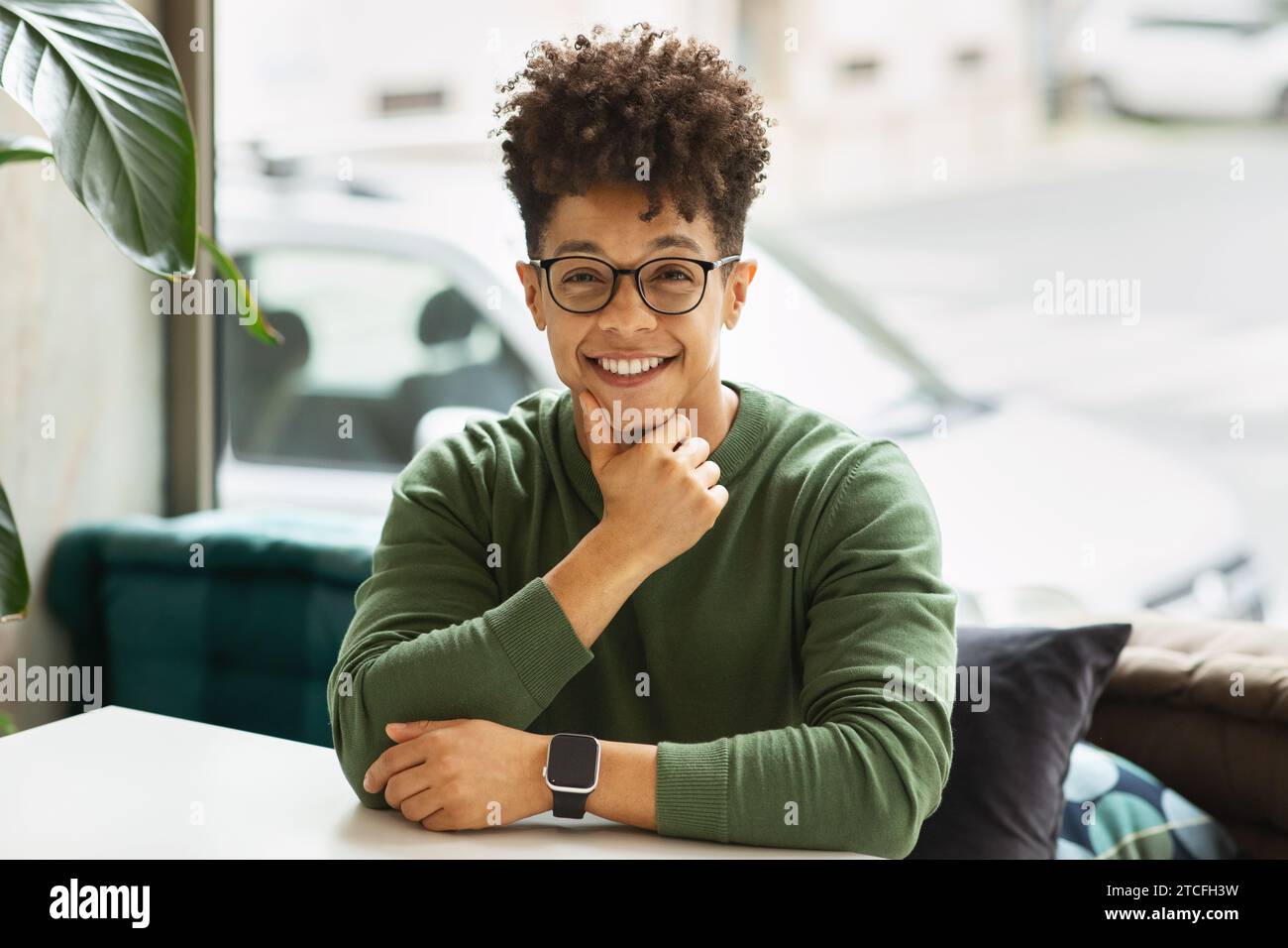 Portrait of positive cool young black man sitting at cafe Stock Photo