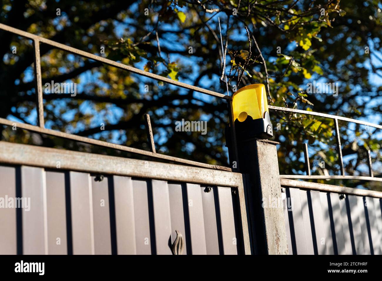 bright yellow flashing light on a private house gate, enhancing security measures. Designed to deter trespassers and provide peace of mind for homeown Stock Photo
