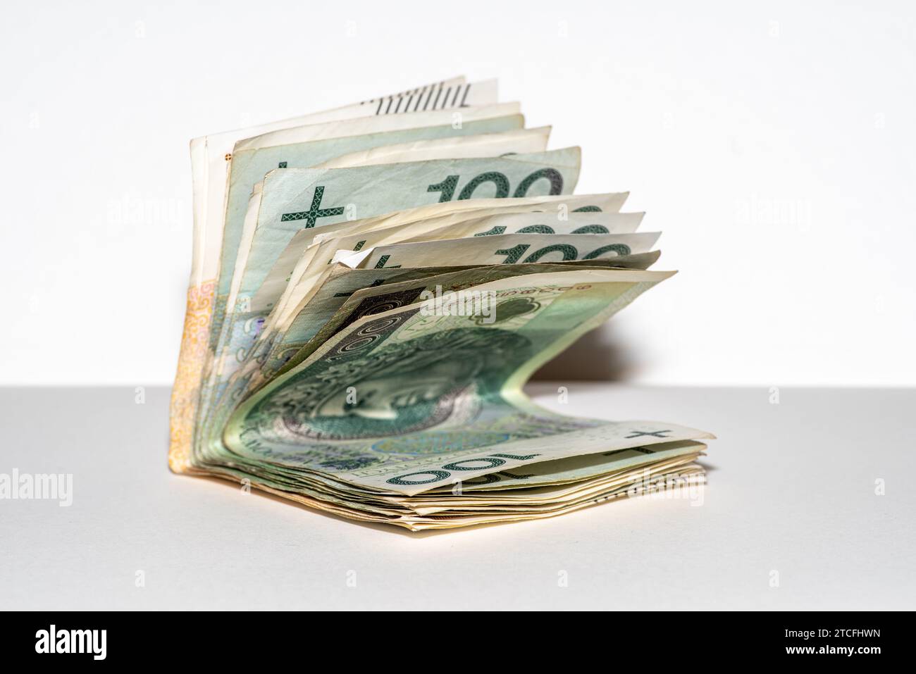A pile of crisp one hundred dollar bills, tightly bound with a blue band Stock Photo