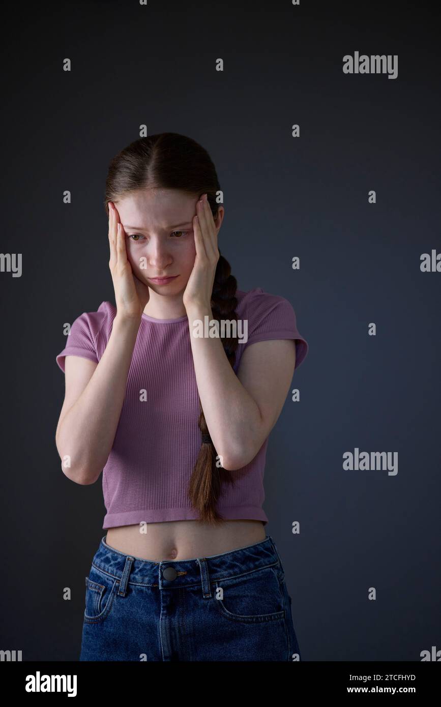Low Key Studio Portrait Of Stressed Teenage Girl Worried About Mental Health Issues Or Bullying Stock Photo