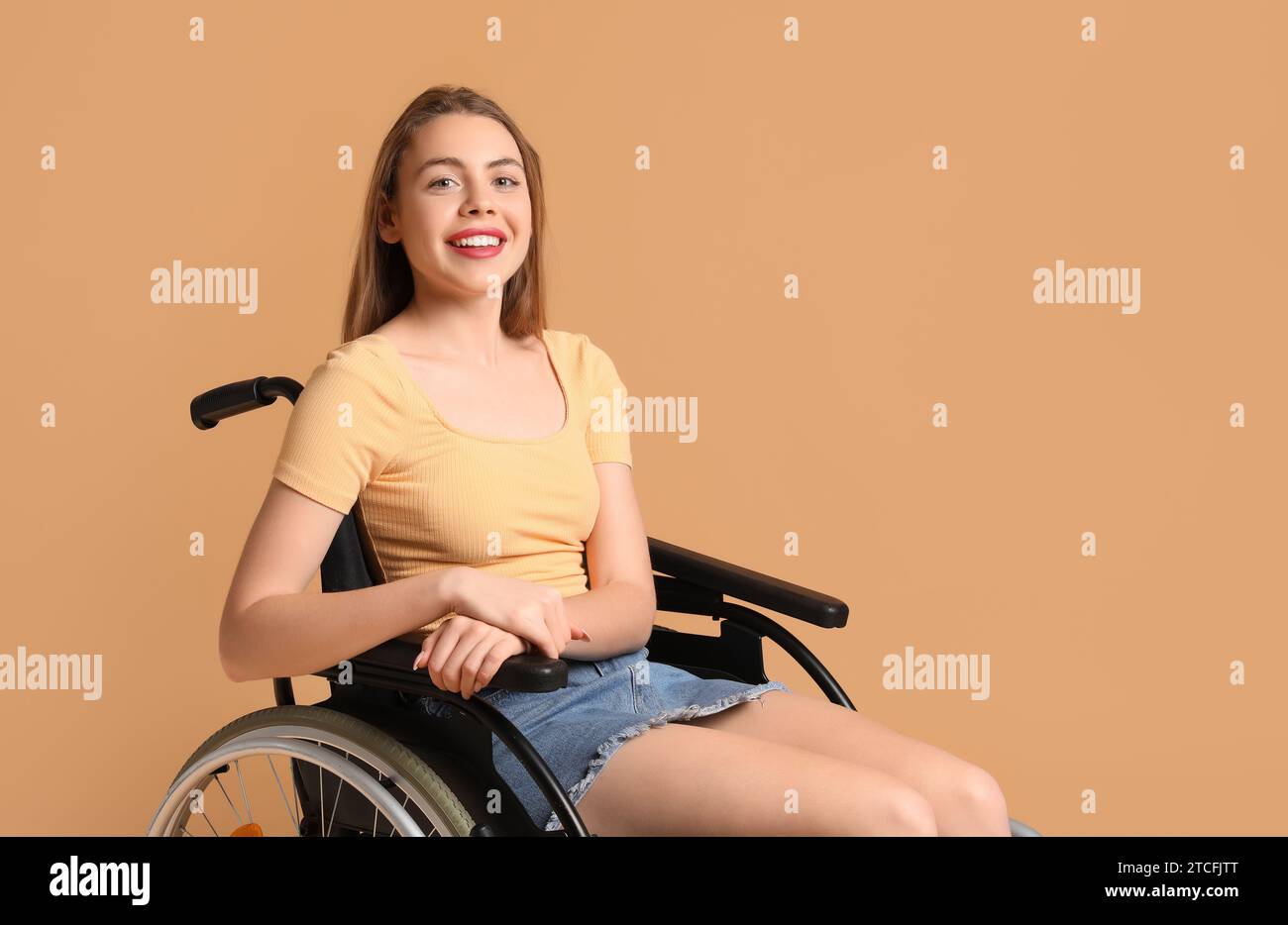 Young woman in wheelchair on beige background Stock Photo - Alamy
