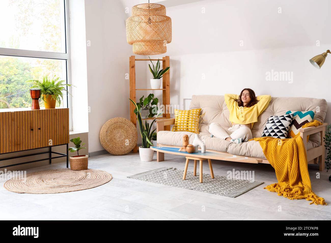 Pretty young woman sitting on white sofa in light living room Stock ...