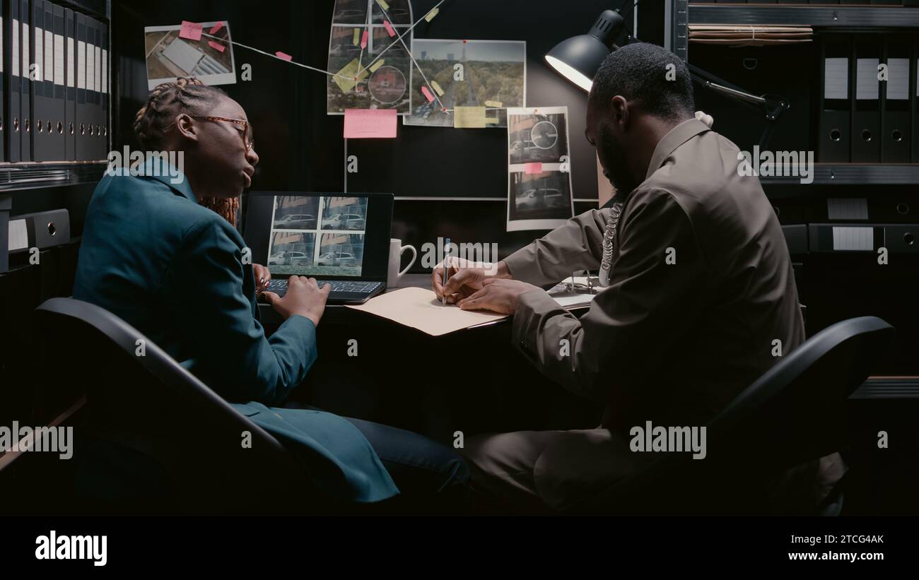 Two police officers analyzing surveillance footage, working on case