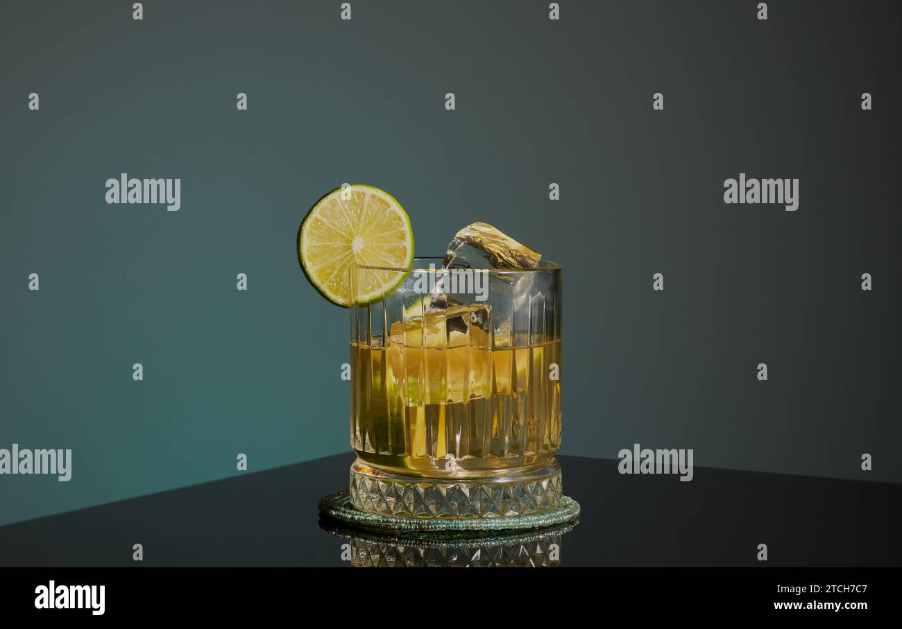 Whisky cocktail garnished with a slice of lime and served with ice rocks. Stock Photo