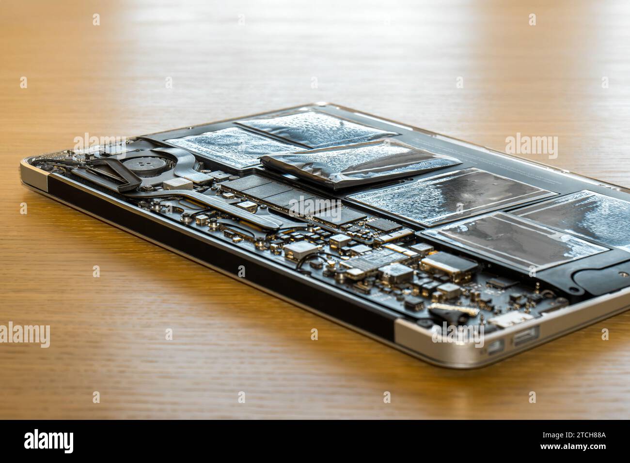 Swollen battery of broken laptop in open casing closeup. Heavy damage