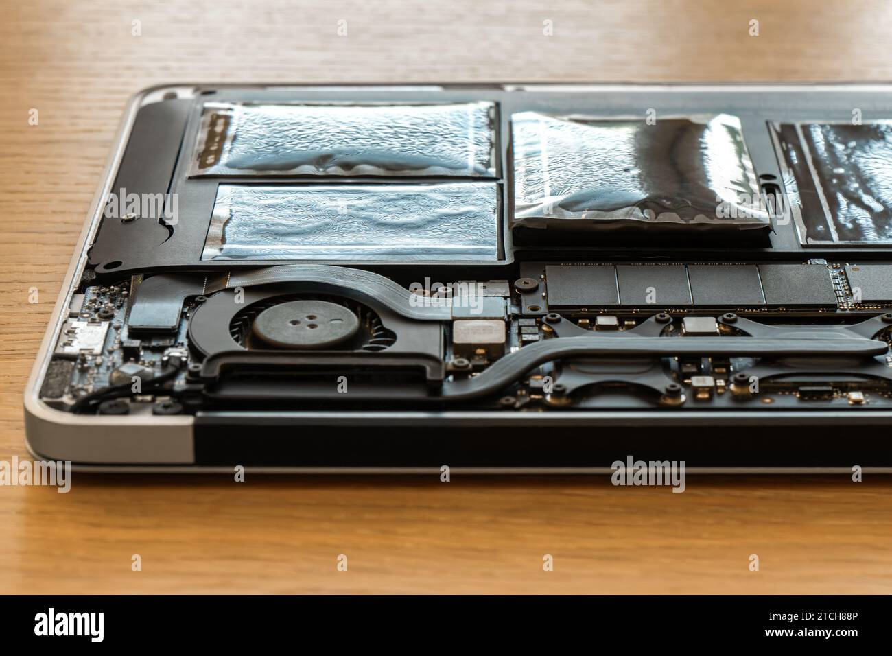 Swollen battery of broken laptop in open casing closeup. Heavy damage of notebook computer