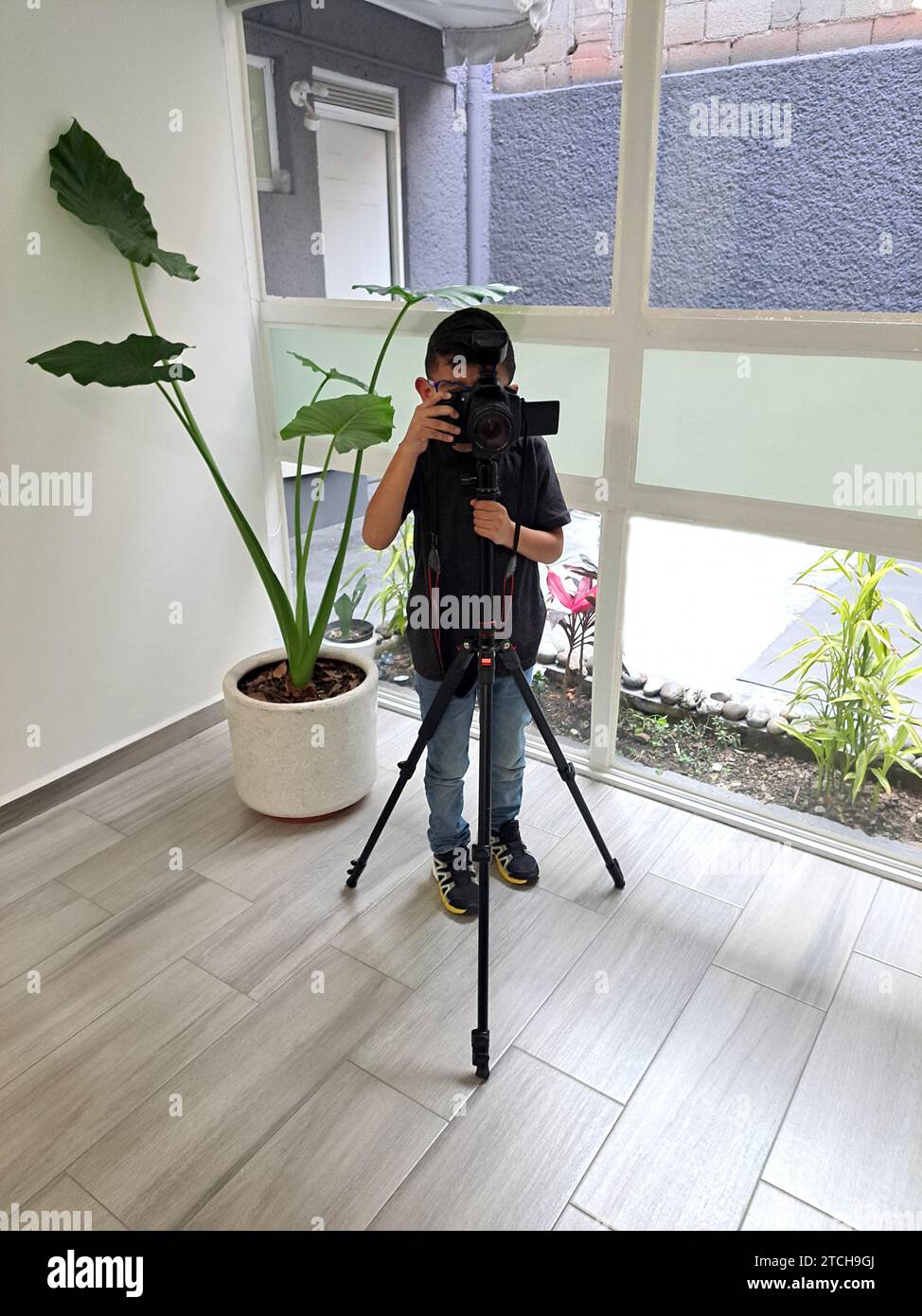 7-year-old Latino boy practices taking photographs with a professional ...