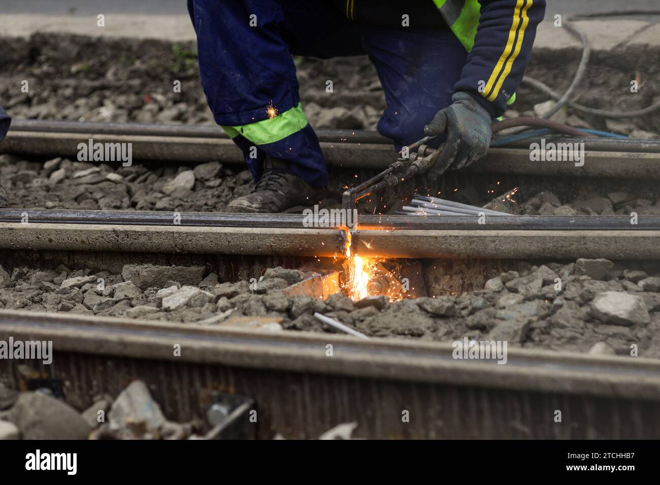 Details with a worker using an oxy-acetylene torch to cut metal tramway tracks. Stock Photo