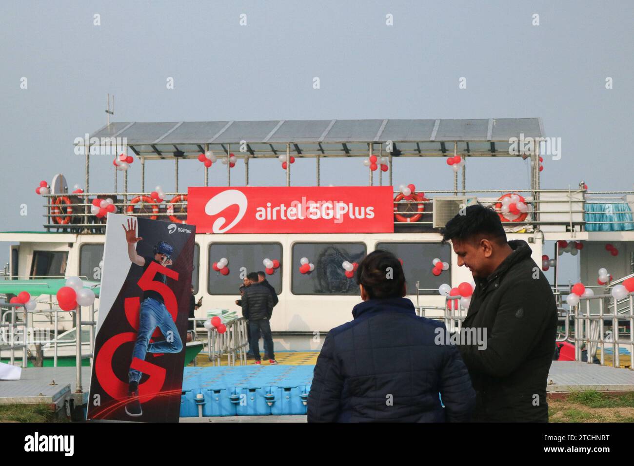 Bharti Airtel Unveils Cutting-Edge 5G Technology December 12,2023, Srinagar Kashmir, India : People stand past logo of Airtel 5G Plus is seen during live 5G plus experience in Srinagar. Airtel announced the launch of its cutting edge 5G services in October, 2022 in 8 cities in India. Today, Airtel s services are live across all states and union territories of India with over 50 million customers as on October 1st, 2023. Srinagar Kashmir India Copyright: xFirdousxNazirxxEyepixxGroupx Stock Photo
