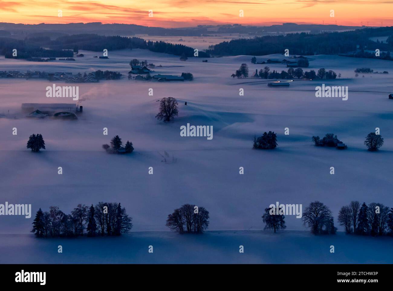 Drone photo of the Bavarian landscape with city view Ruderatshofen with fog in the evening short after sunset in Marktoberdorf, Germany, Dec 3, 2023. Stock Photo