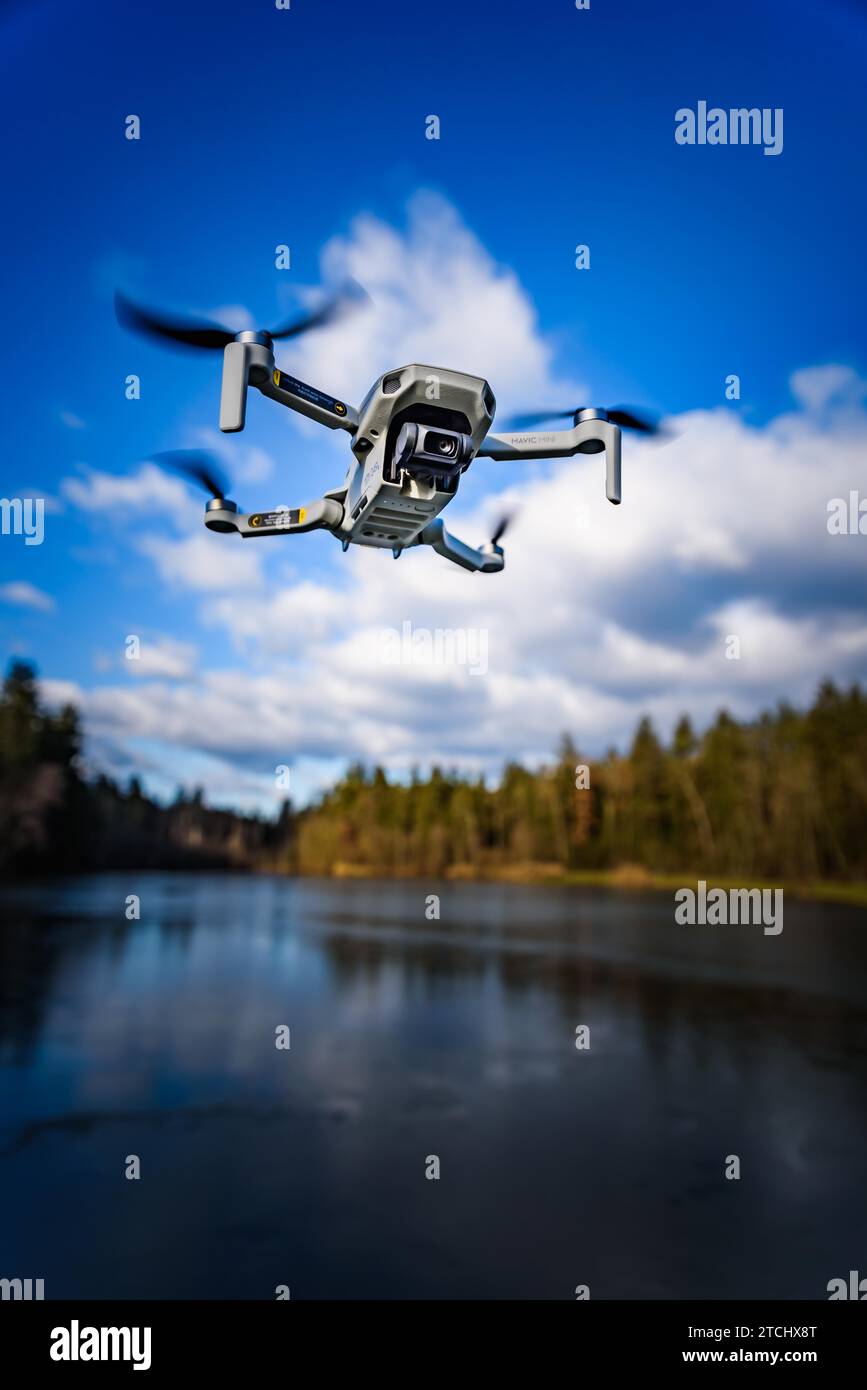 Graz, Austria, December 29 2019. DJI Mavic Mini drone flying in the countryside above frozen lake on sunny winter day. Drone flying Stock Photo