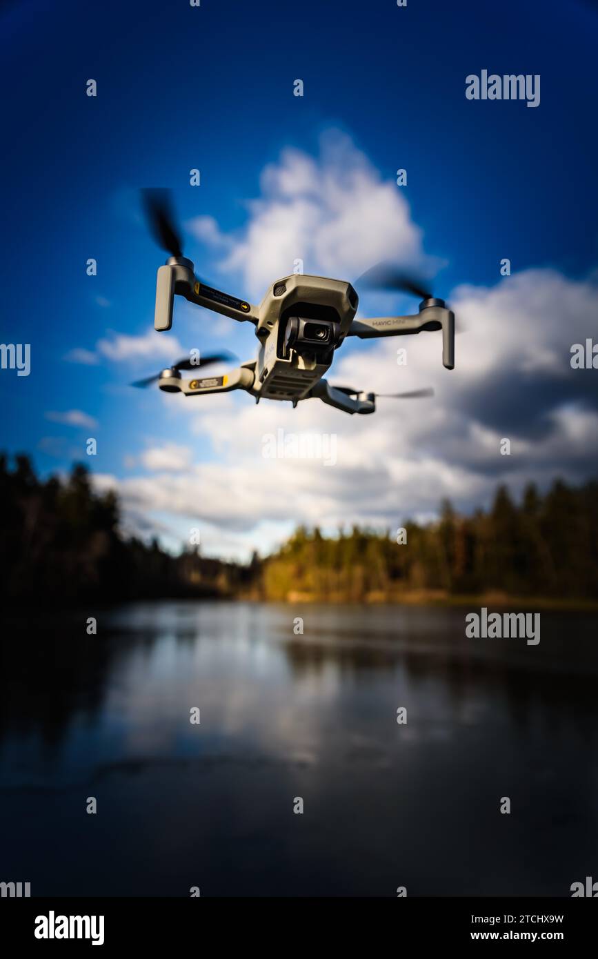 Graz, Austria, December 29 2019. DJI Mavic Mini drone flying in the countryside above frozen lake on sunny winter day. Drone flying Stock Photo