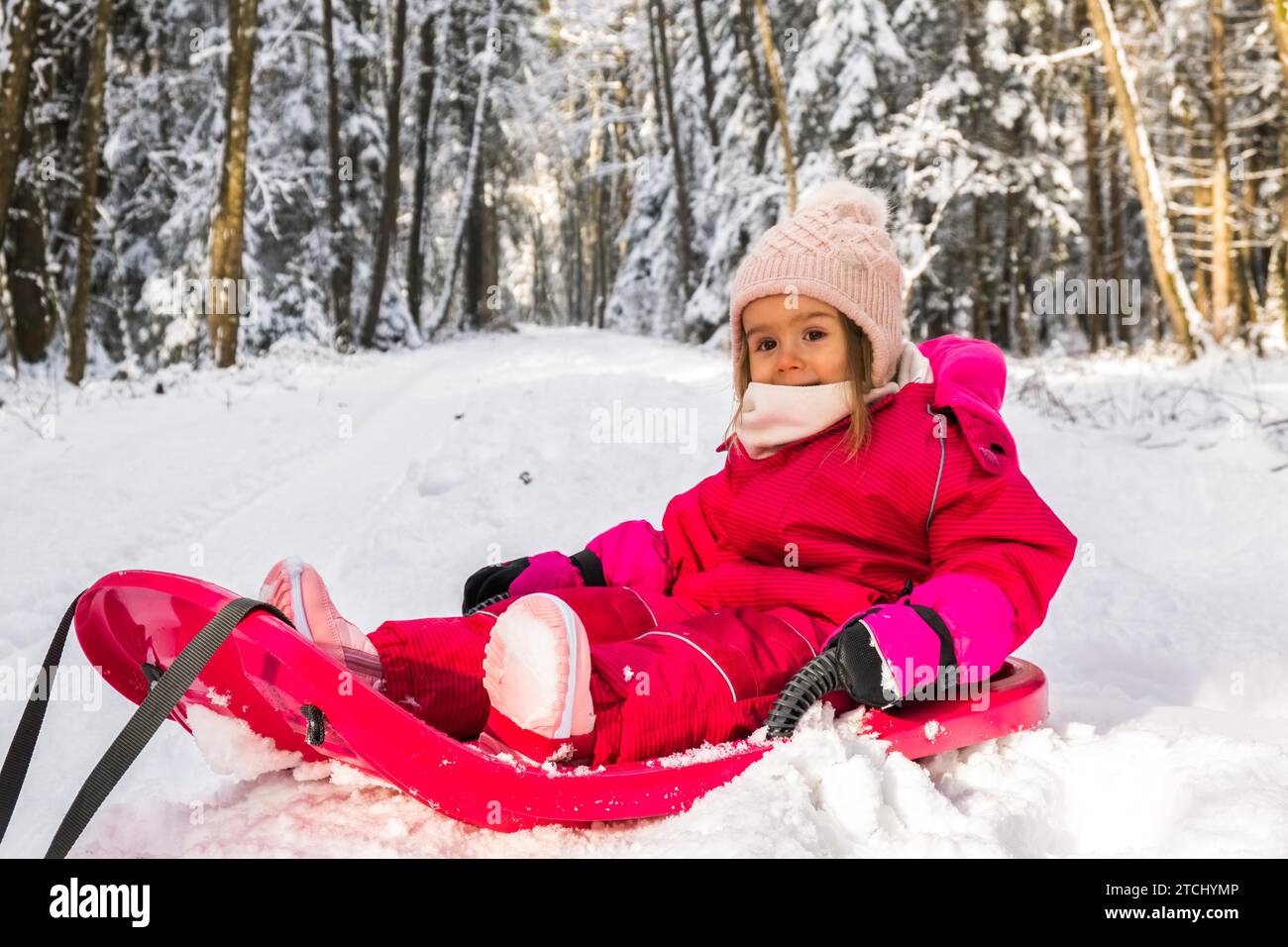 Baby on a sled on path in winter forest. Snowy woods theme Stock Photo ...