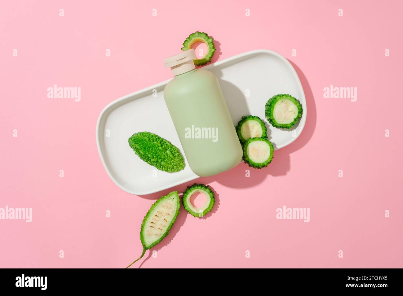 A cosmetic bottle and bitter melon are placed on a ceramic tray on a