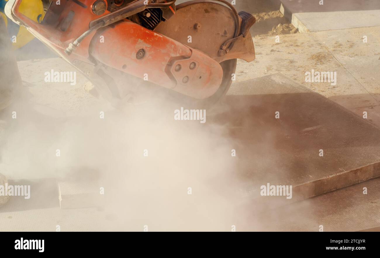 Builder cutting concrete slabs with petrol concrete saw and a diamond