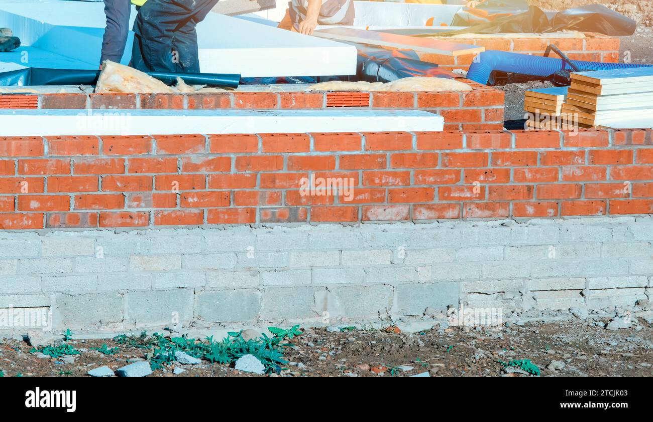 Builder placing polystyrene insulation boards on waterproofing membrane