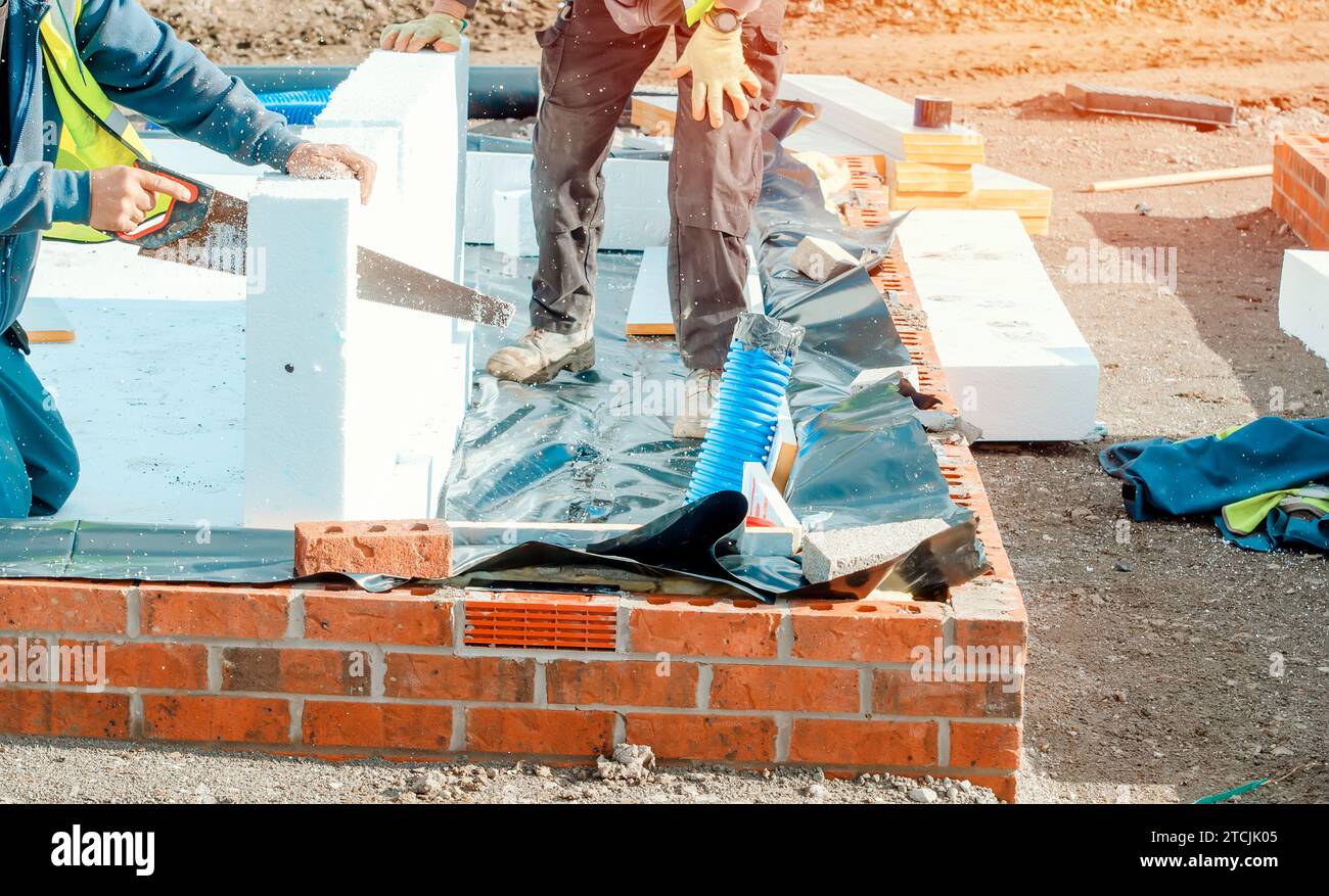 Builder placing polystyrene insulation boards on waterproofing membrane