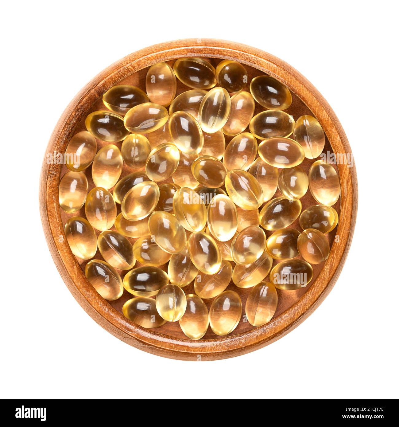 Soft gel capsules in a wooden bowl. Oral dosage medicine or dietary supplement in the form of a transparent capsule. Stock Photo