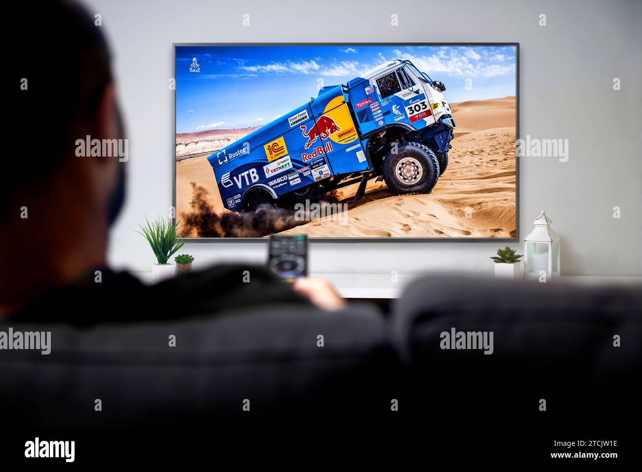 Man watching Dakar rally race on smart TV. Sports Live transmission concept. ROSARIO, ARGENTINA - DECEMBER 2, 2023. Stock Photo