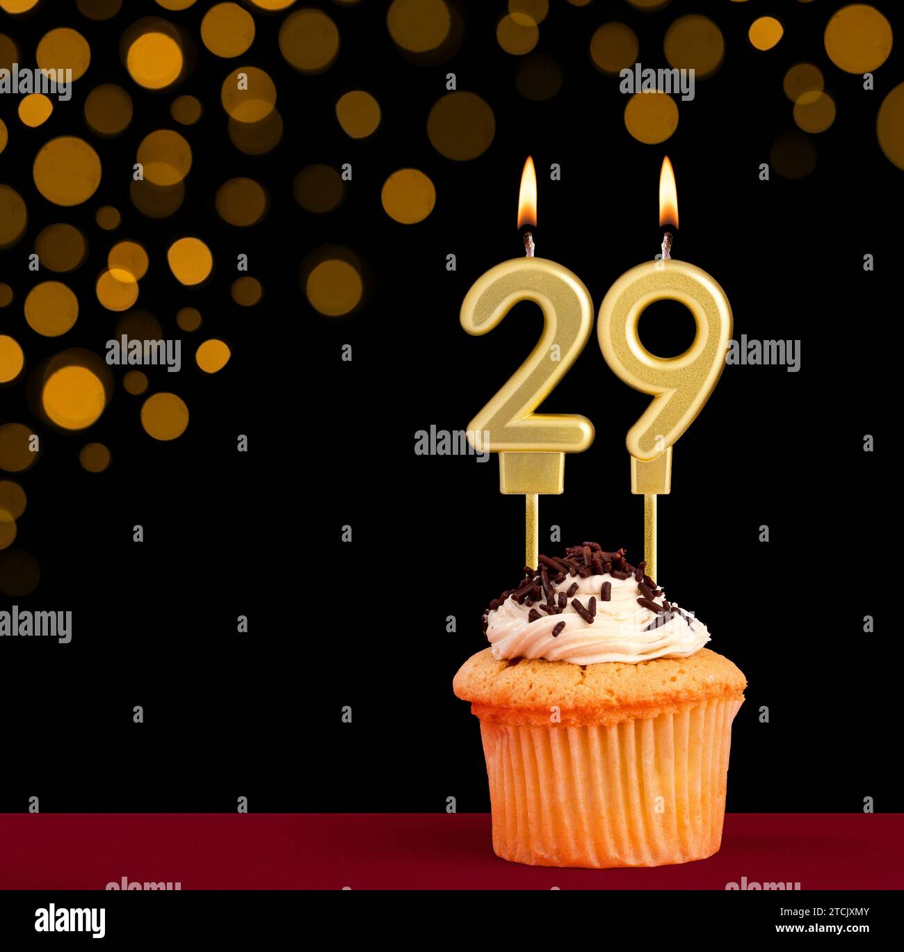 Number 29 birthday candle - Cupcake on black background with out of focus lights Stock Photo