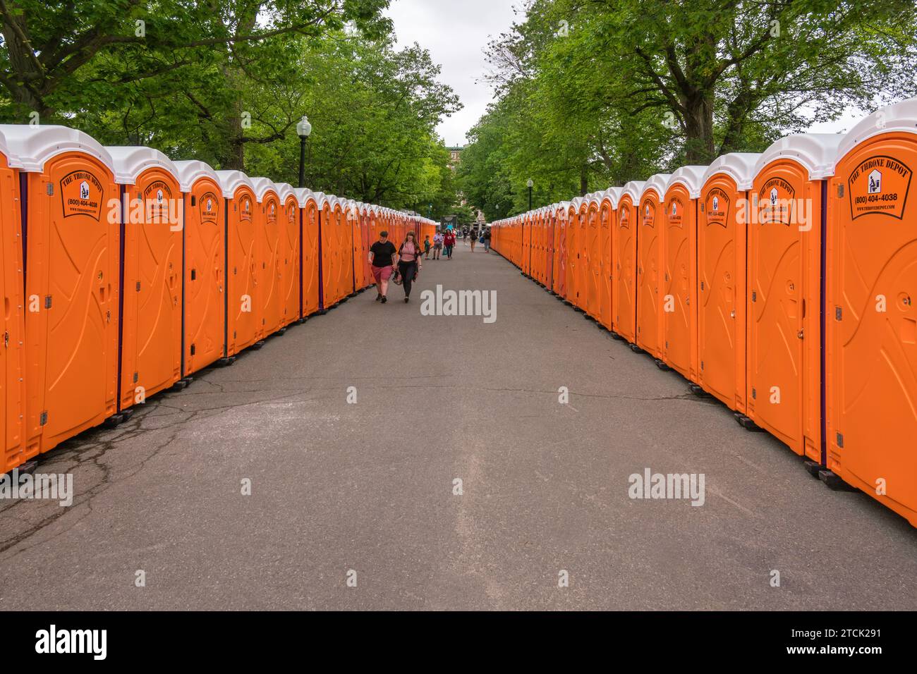 Boston, MA US-June 10, 2023: Two rows of orange portable toilets at a large outdoor event. Stock Photo