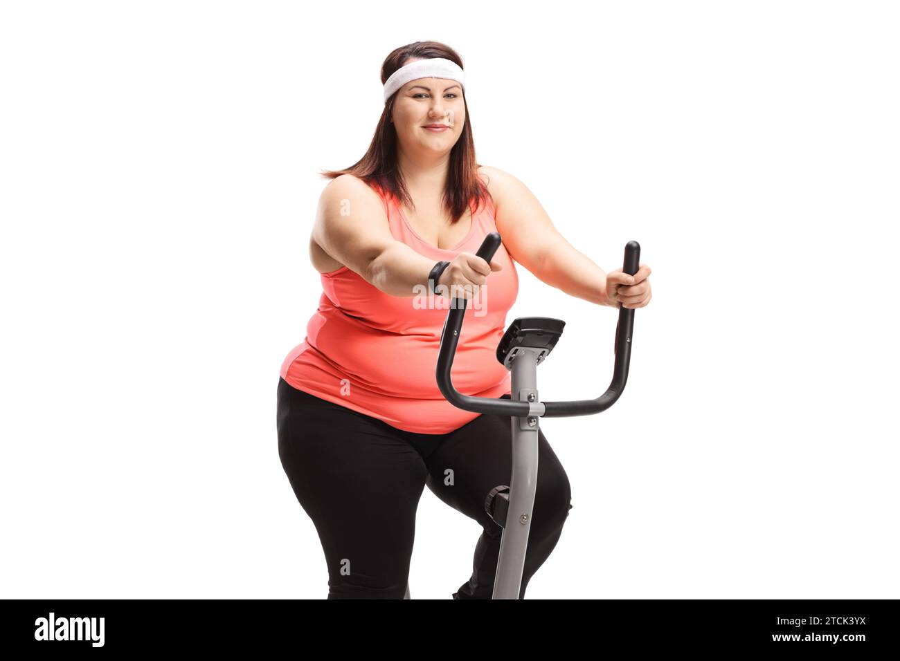 Young woman riding a stationary bike and looking at the camera isolated on white background Stock Photo