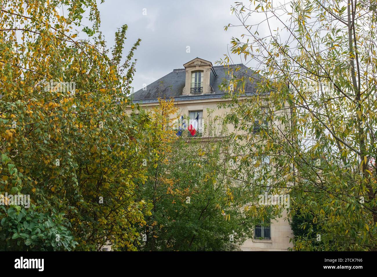 Paris, France, 2023. The façade of the Bibliothèque de l'Arsenal as seen through the yellowing foliage of trees in the Jardin Teilhard de Chardin Stock Photo