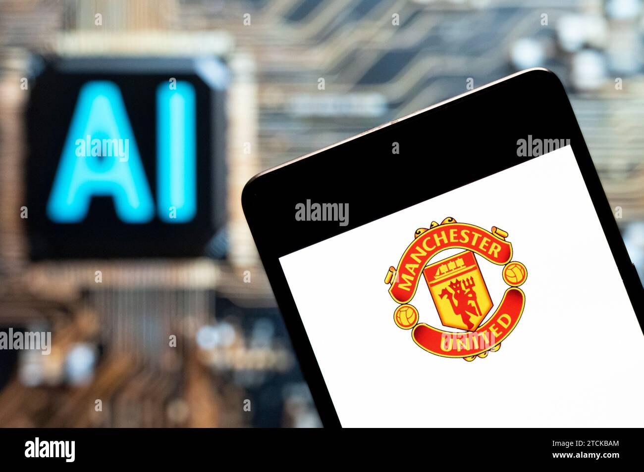 In this photo illustration, the professional premier league football club Manchester United (MU) logo seen displayed on a smartphone with an Artificial intelligence (AI) chip and symbol in the background. Stock Photo
