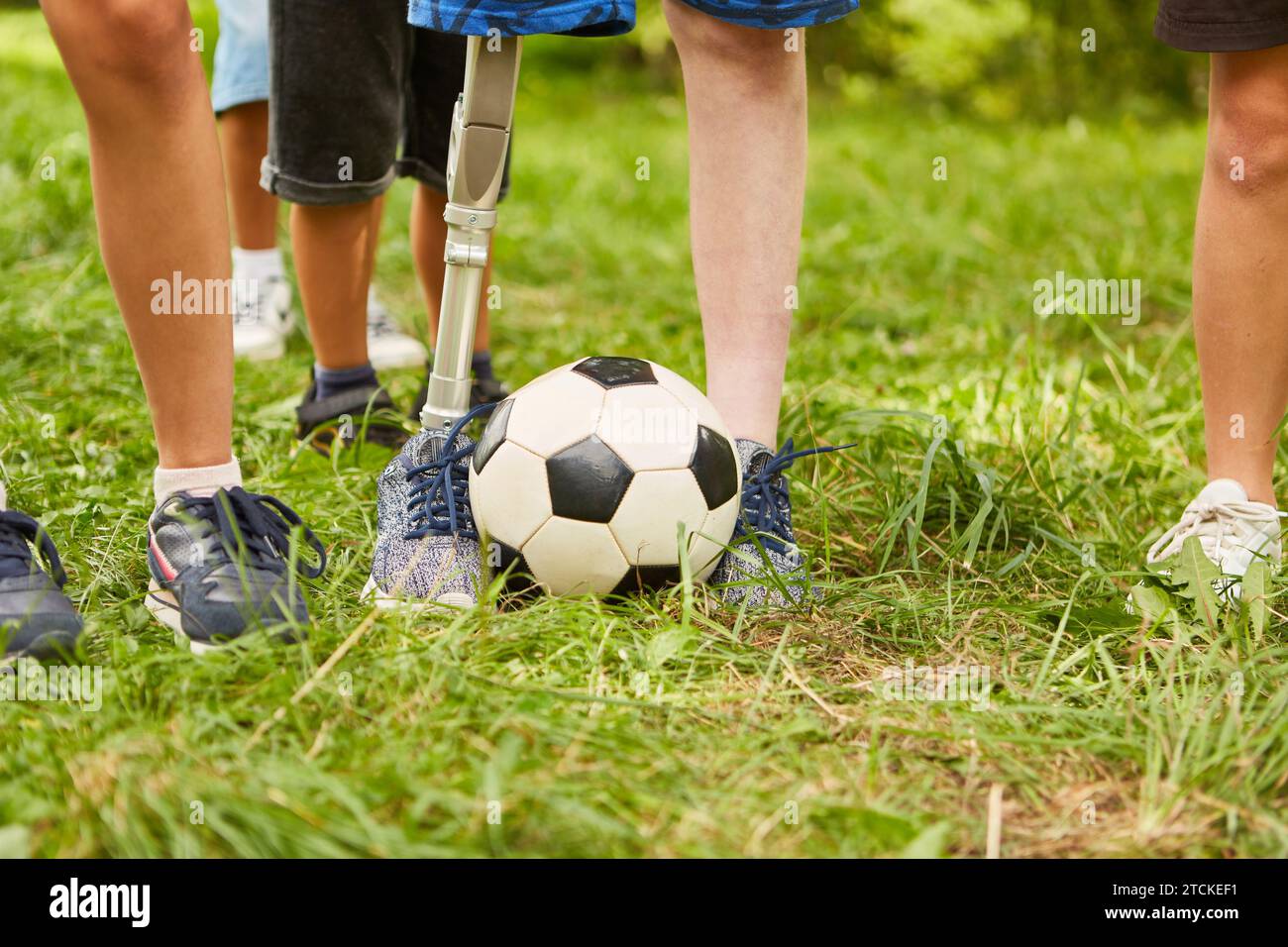 Low section of boy with amputated leg playing soccer while standing at park Stock Photo