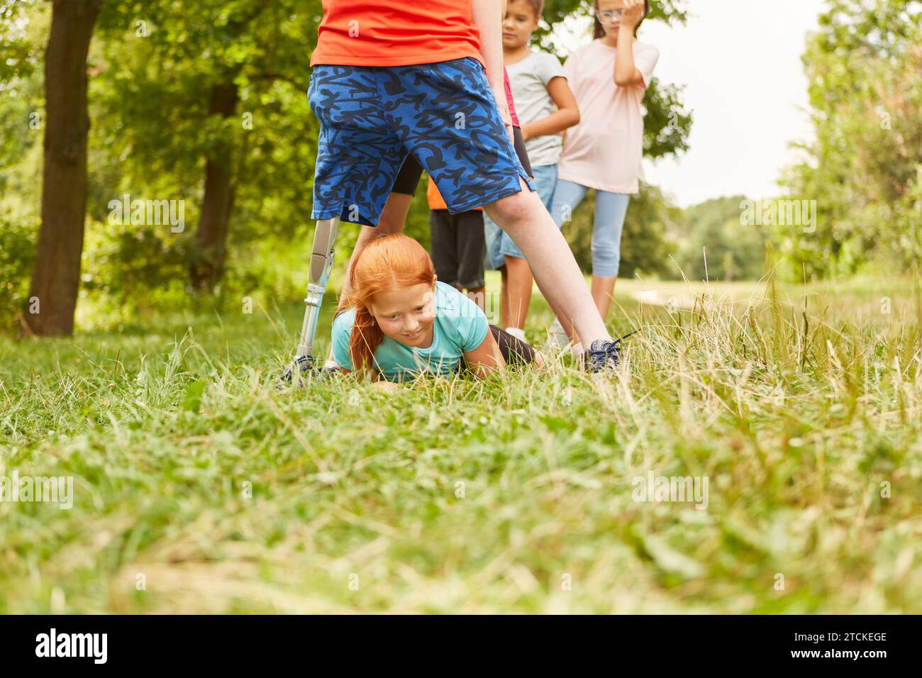 Girl crawling under male and female friends while playing at park Stock Photo