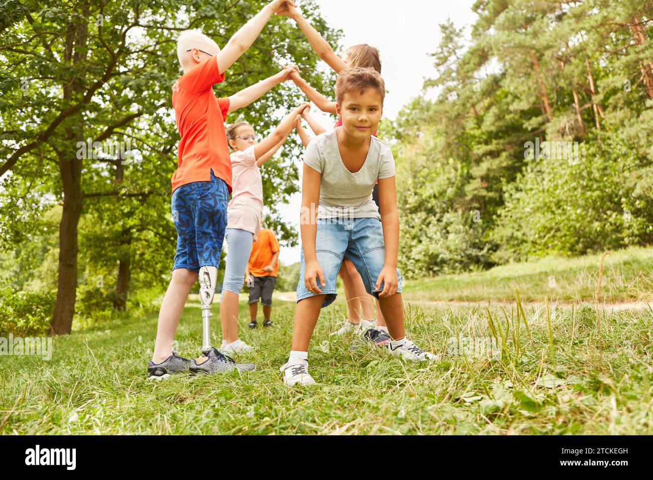 Boy standing near friends playing together and having fun at park Stock Photo