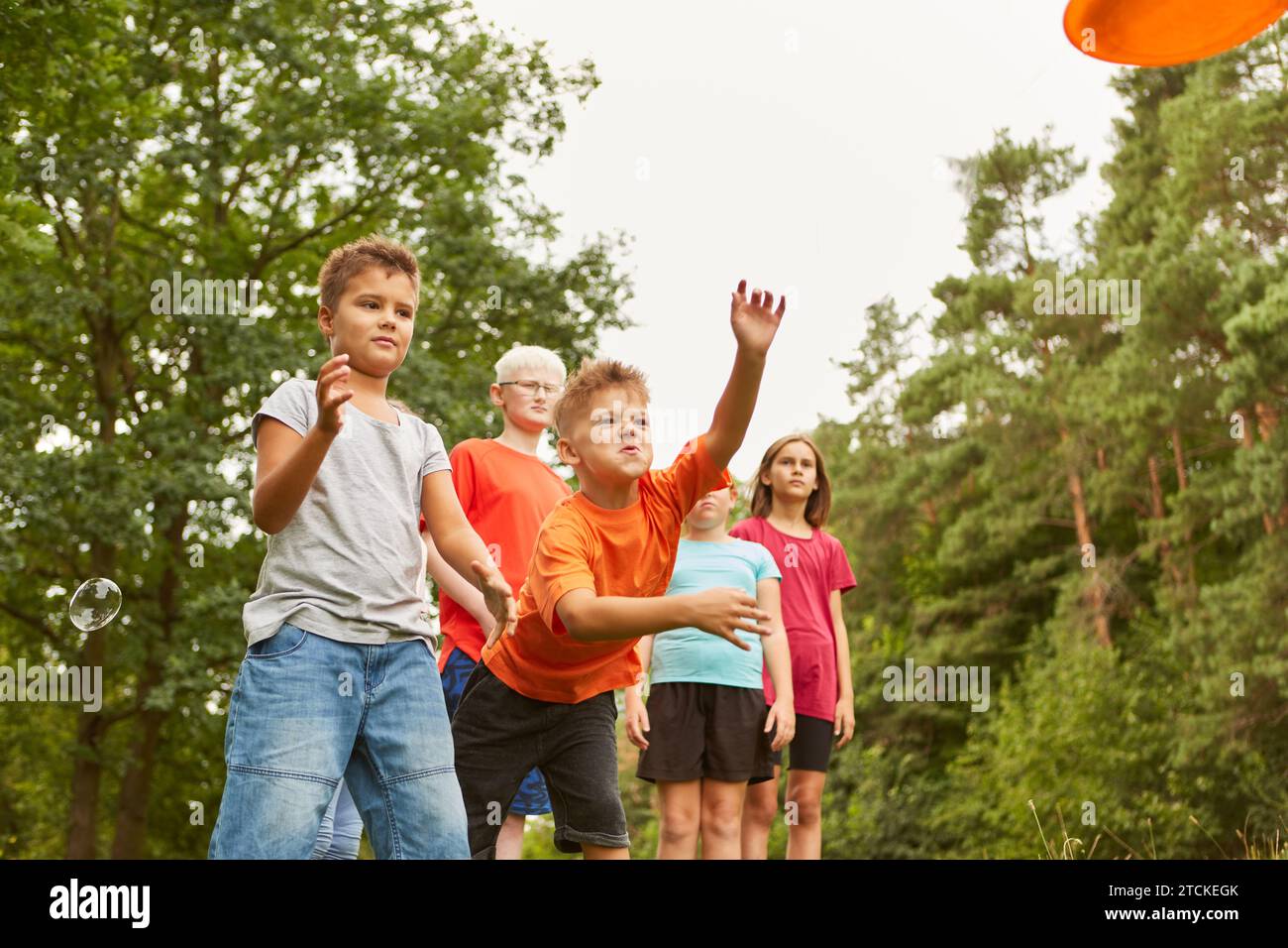 Playful boy throwing frisbee while playing with friends at park Stock Photo