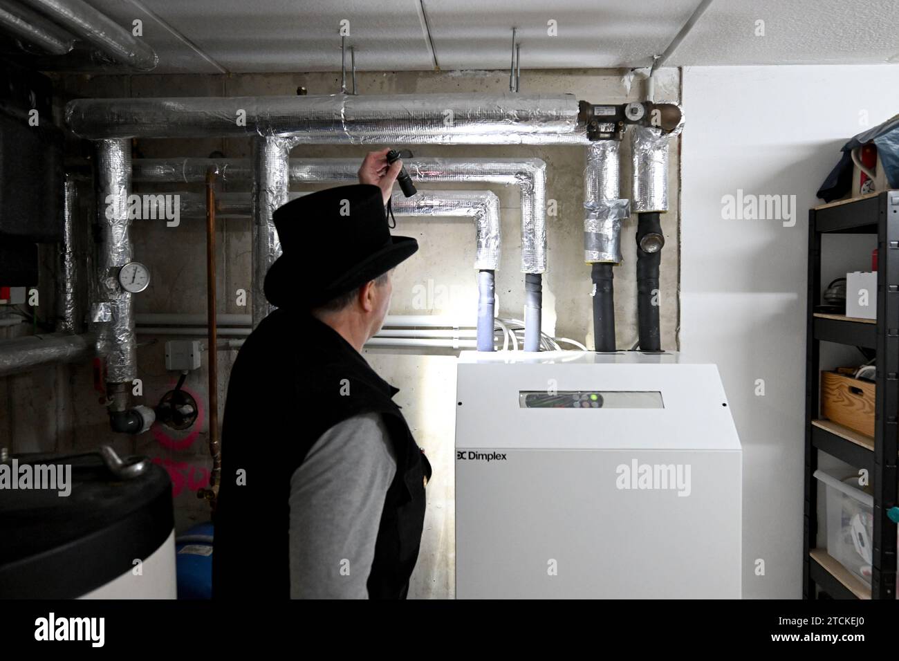 Munich, Germany. 13th Dec, 2023. Chimney sweep Udo Löbel inspects a water-to-water heat pump with a well in the basement of a detached house. From January, only heating systems based on 65 percent renewable energy may be installed in new buildings in new development areas. In many cases, this is likely to be a heat pump. Credit: Felix Hörhager/dpa/Alamy Live News Stock Photo