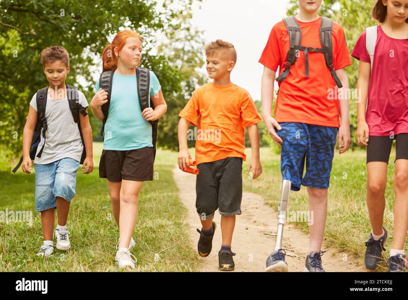 Male and female friends walking with disabled boy on footpath at forest Stock Photo
