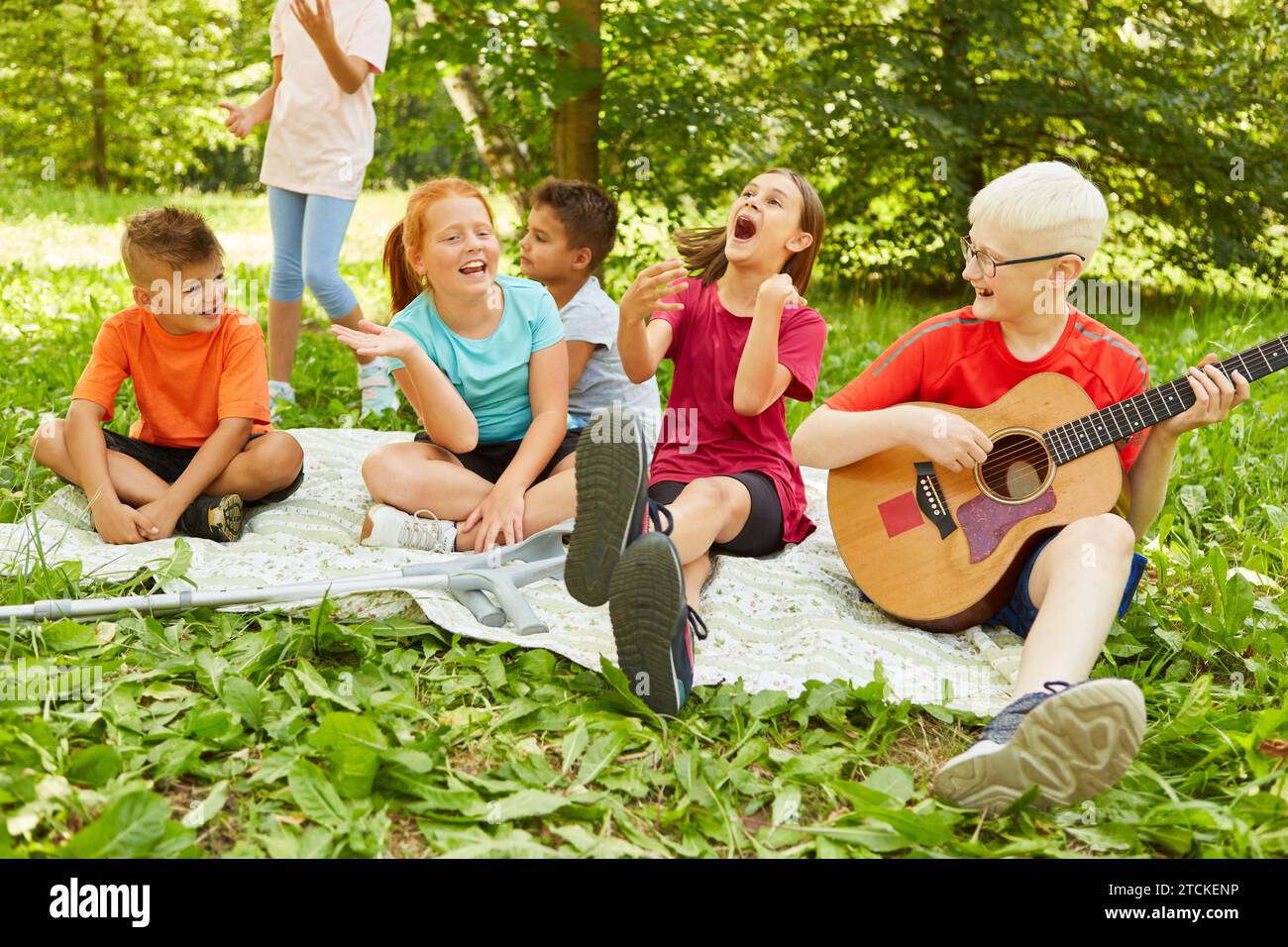Carefree male and female friends having fun while sitting on blanket at park Stock Photo