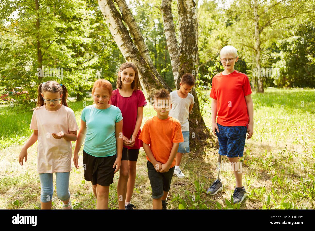 Portrait of smiling kids standing with male handicapped friend at park Stock Photo