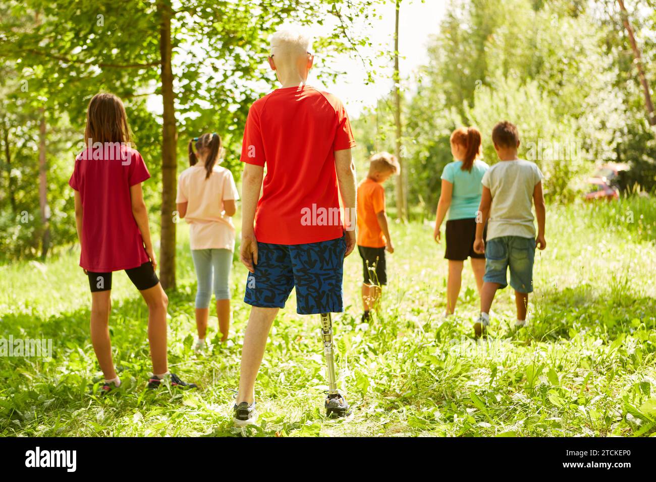 Rear view full length of disabled boy standing with friends at park Stock Photo