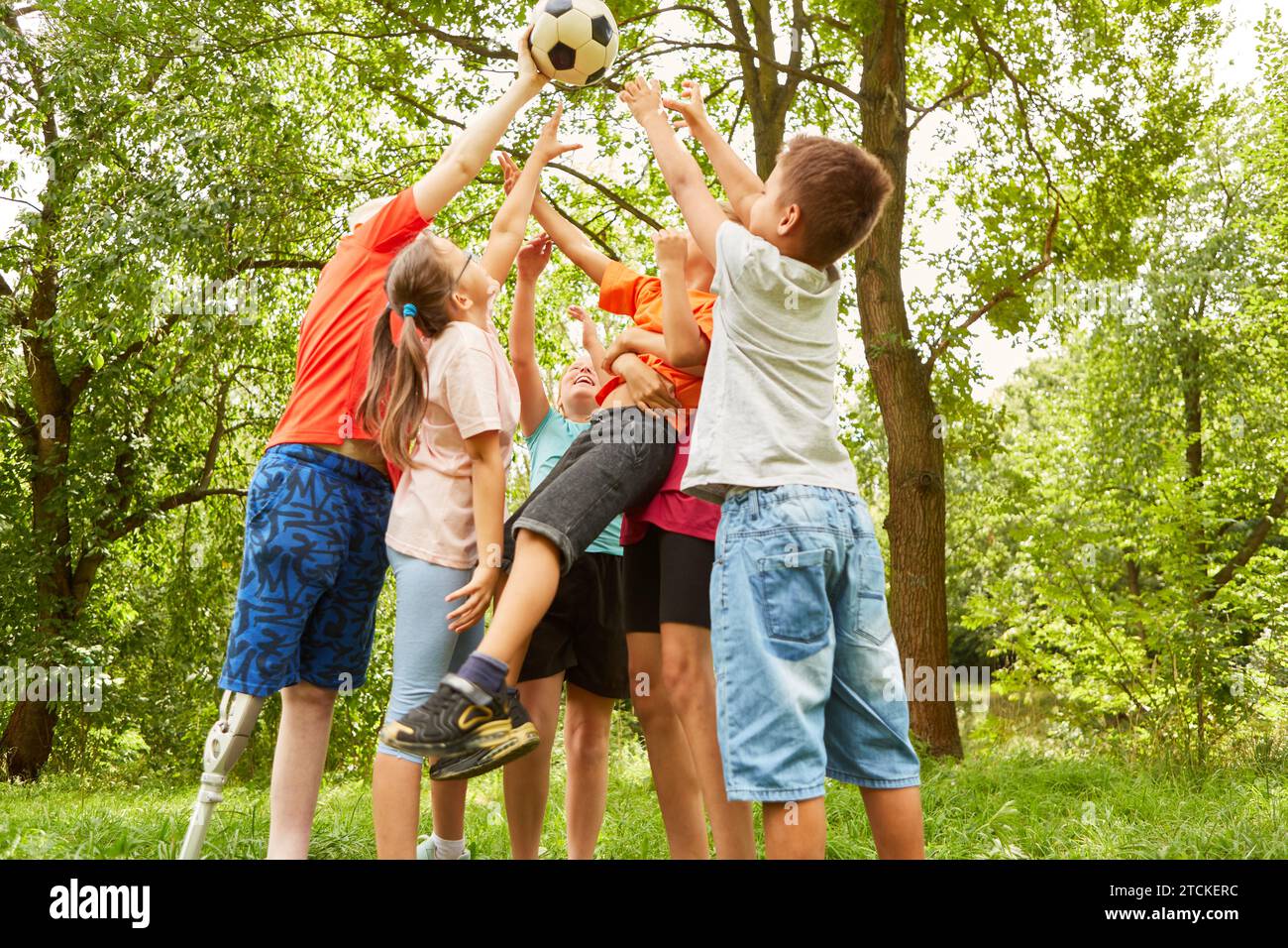 Happy male and female friends playing with soccer ball while standing at park Stock Photo