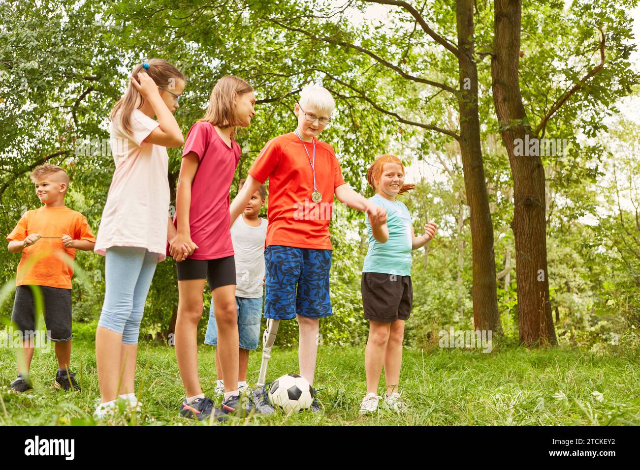 Disabled boy holding hands with friends while playing soccer at park Stock Photo